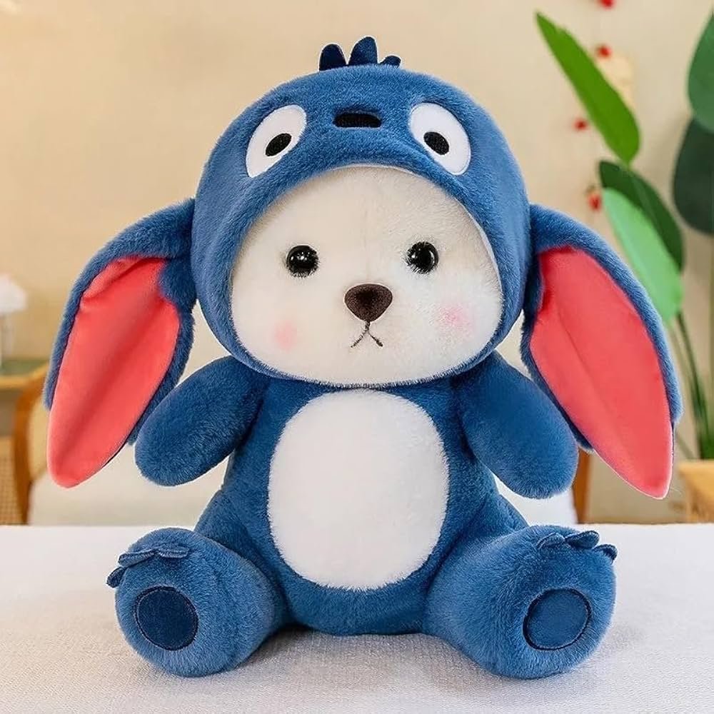 "Plush toy bear in a cute blue animal costume with floppy ears, sitting on a table indoors."
